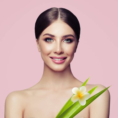 Gülümseyen kadın tropikal çiçek ve pembe bir arka plan üzerinde yeşil yaprakları ile cilt bakımı ve cilt bakımı tedavisi