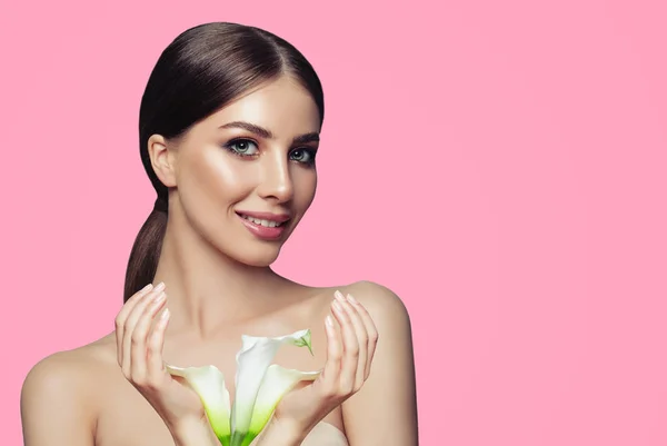 Perfect spa woman with healthy skin, manicured hands and white flowers on pink background. Facial treatment, cosmetology and spa