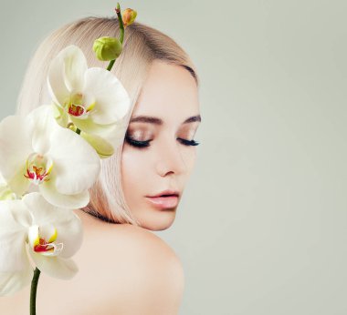 Genç kadın yüz portre. Temiz cilt ve beyaz orkide çiçekleri ile Spa modeli. Yüz tedavi, kozmetik, güzellik salonları, Cilt Bakımı ve spa arka plan