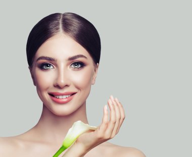 Genç kadın portre yüz. Sağlıklı cilt ve afiş arka plan üzerinde beyaz çiçek gülümseyen kadın