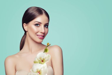 Genç kadın makyaj ve Pastel mavi arka plan, güzellik portre üzerinde orkide çiçekleri ile mükemmel
