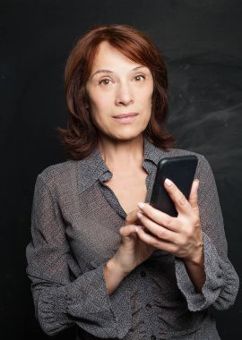 Smartphone tutan olgun iş kadın. İş kadını cep telefonundan tahta arka plan ile