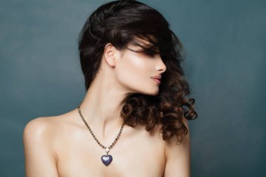 Güzel esmer kadın takı kolye. Mavi afiş arka plan üzerinde siyah kıvırcık saçlı seksi kadın modeli