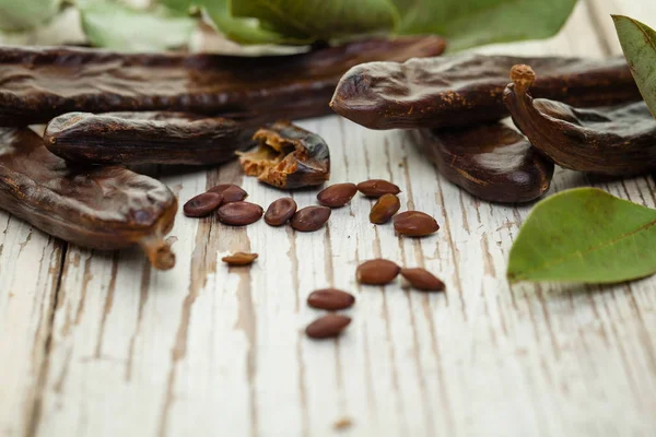 Carob Ekologiskt Carob Baljor Med Frön Och Blad Vit Träbord — Stockfoto