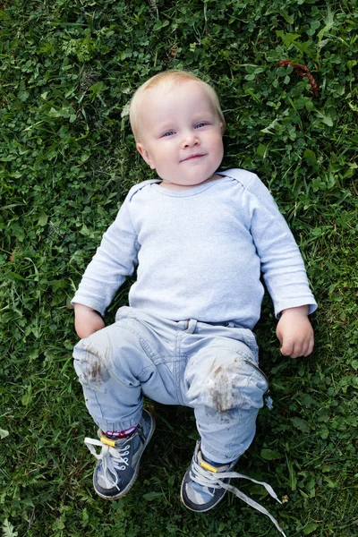 Niedlicher Kleiner Junge Lächelt Während Auf Dem Grünen Gras Liegt — Stockfoto