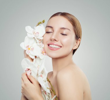 Spa Güzellik. Sağlıklı cilt, şirin kadınla mükemmel bir gülümseme ve beyaz arka plan üzerinde çiçek gülümseyen. Kozmetik, yüz tedavi ve sağlık kavramı 