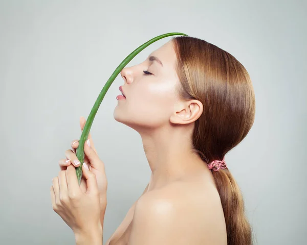 美丽的女人与健康的头发和清澈的皮肤举行绿色芦荟叶 — 图库照片