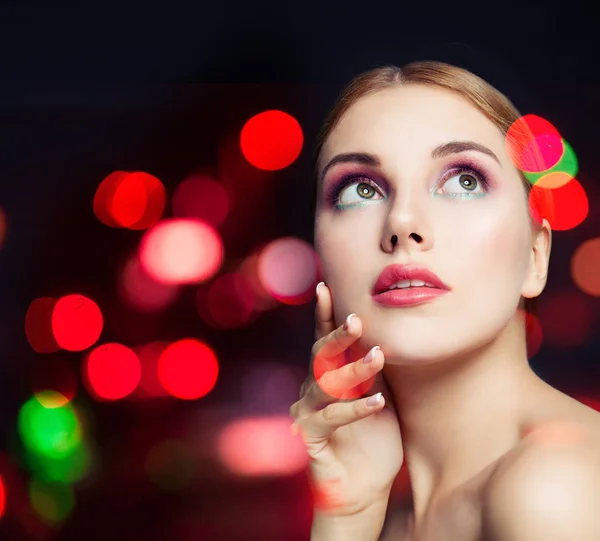 Attractive female model woman with colorful makeup on bokeh glitter background