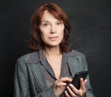 Smartphone manifatura olan orta yetişkin kadın. İş kadını ile cep telefonu