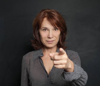 Gülümseyen ve siyah arka plan üzerine işaret mutlu olgun iş kadını