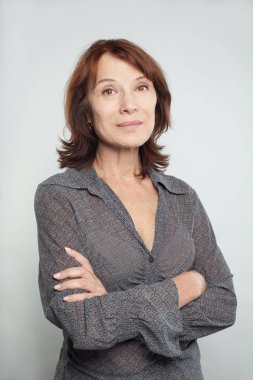 Beyaz üzerine çapraz kolları olan orta yetişkin iş kadını gülümseyen