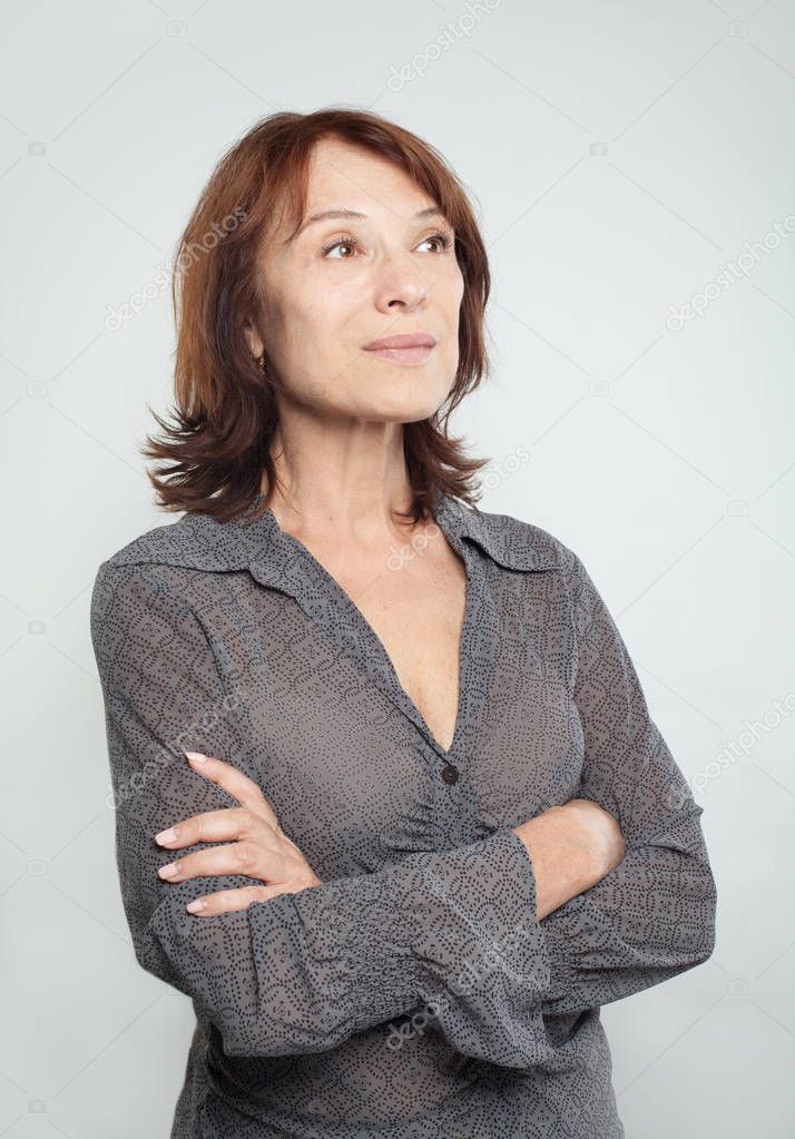Confident business woman with crossed arms looking up on white background