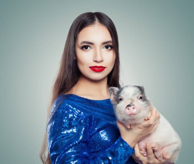 Küçük domuz tutan mavi glitter elbiseli güzel esmer kadın