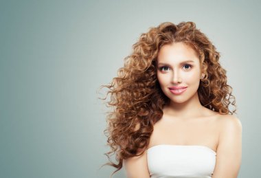 Gri arka plan üzerinde uzun sağlıklı dalgalı saçlı Kızıl saçlı kız