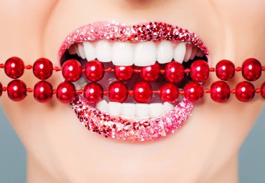 Kırmızı dudaklar ve parlak inci closeup ile beyaz sağlıklı dişler. Mükemmel kadın gülümseme glitter ruj makyaj ile 
