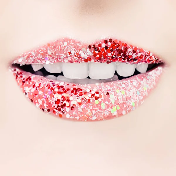 Red lips with glamorous glitter lipstick makeup closeup. Cheerful female smile with white teeth