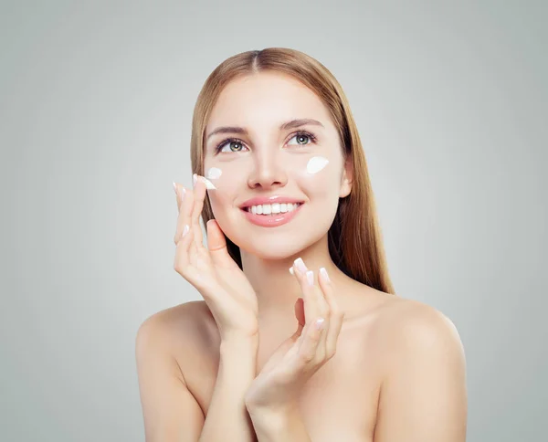 Mujer Alegre Aplicando Crema Cosmética Facial Sonriendo Sobre Fondo Blanco — Foto de Stock