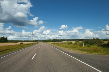 Alanlar, ağaçlar ve mavi gökyüzü ve bulutlar olan yol. Güneş gün.