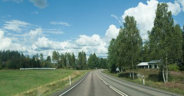 Finlandiya'da yol. Mavi gökyüzü ve beyaz bulutlar