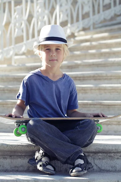 Skater garçon en bleu T-shirt assis avec un longboard — Photo