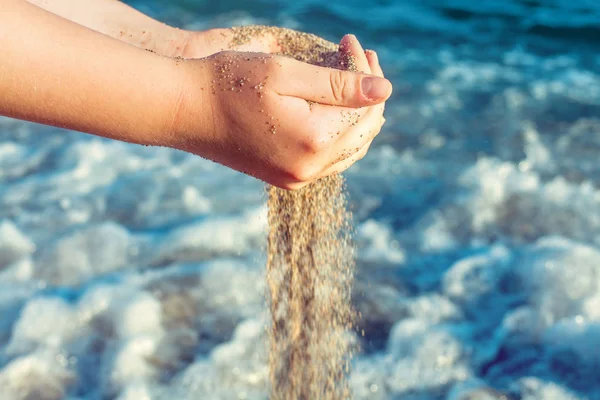 Písek padající z rukou na sea beach pozadí. Příjemné svátky — Stock fotografie