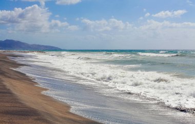 Siyah kum ve yaz gökyüzü ile deniz plaj
