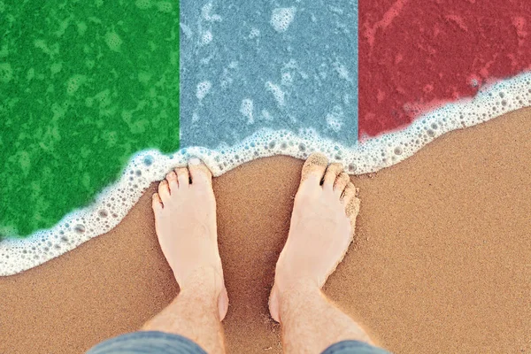 Feet on the sunny sandy beach with flag Italy. Top View on sea — Stock Photo, Image