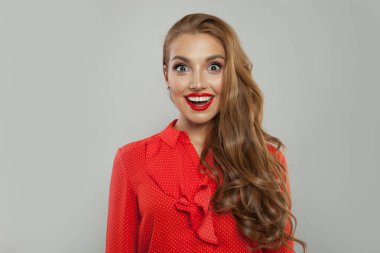 Heyecanlı model beyaz arka planda gülümsüyor. Genç sürpriz kadın