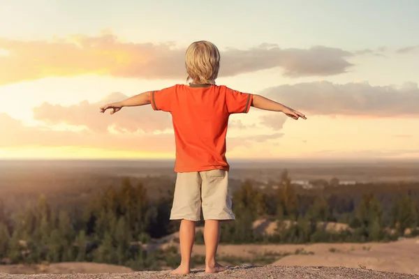 Kid Boy levantó las manos contra el atardecer de fondo —  Fotos de Stock