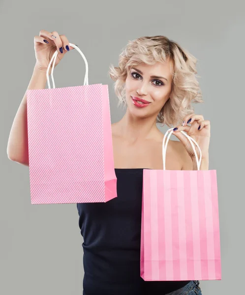 Mujer modelo bonita mostrando dos bolsas de compras de color rosa y sonriendo — Foto de Stock