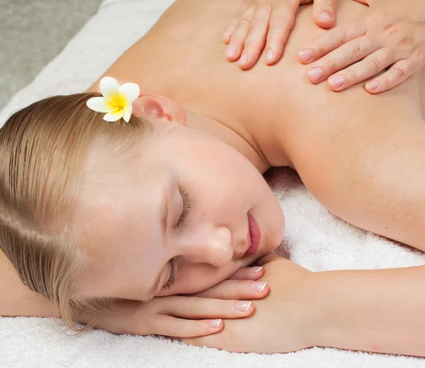 Спа масаж. Красива молода жінка з тропічною квіткою отримує спа-масаж — стокове фото