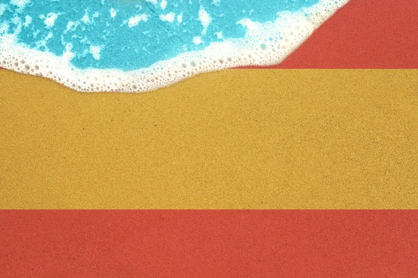 Sea wave on the sunny sandy beach with flag Spain. View from top on surf — Stock Photo, Image