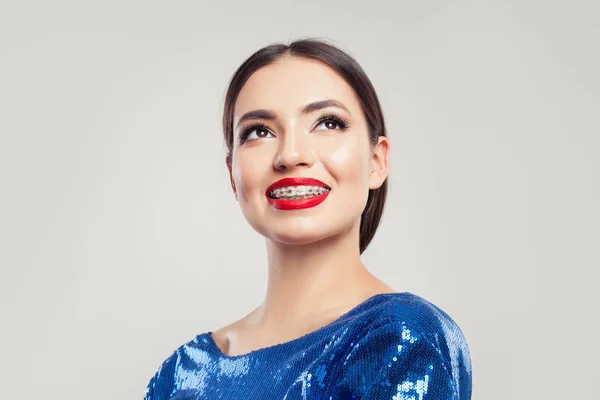 Cheerful girl in braces smiling and looking up on white background