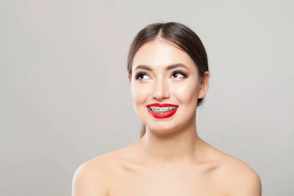 Felice giovane donna in bretelle sui denti sorridente su sfondo bianco — Foto Stock