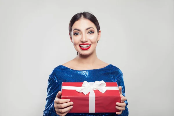 Счастливая молодая женщина в брекетах с красной коробкой подарков с белой лентой — стоковое фото