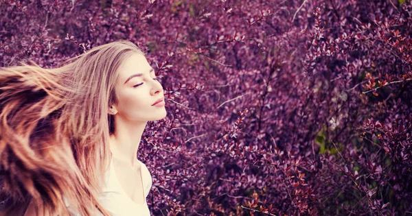 Mulher bonita desfrutando ao ar livre contra flores roxas fundo — Fotografia de Stock