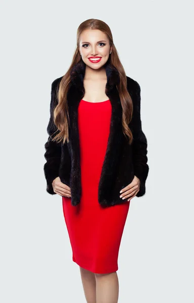 Femme heureuse en robe rouge et manteau noir sur blanc, portrait de mode — Photo