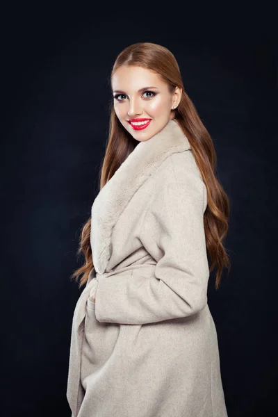 Mulher sorridente bonito em casaco bege posando no fundo preto — Fotografia de Stock