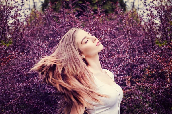 Молода жінка з довгим прямим волоссям на фоні квітів — стокове фото