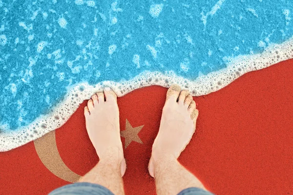 Τα πόδια στην ηλιόλουστη αμμώδη παραλία με σημαία Τουρκία. Κορυφαία προβολή στο surf — Φωτογραφία Αρχείου