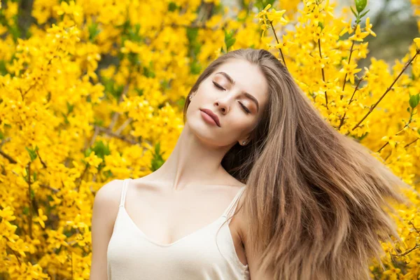 Linda joven al aire libre. Primavera chica con el pelo largo contra flores de fondo —  Fotos de Stock