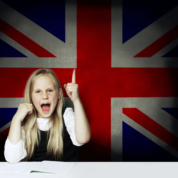 Joyeux enfant fille étudiant pointant vers le haut et s'amusant sur le fond du drapeau britannique. Apprendre la langue anglaise concept — Photo