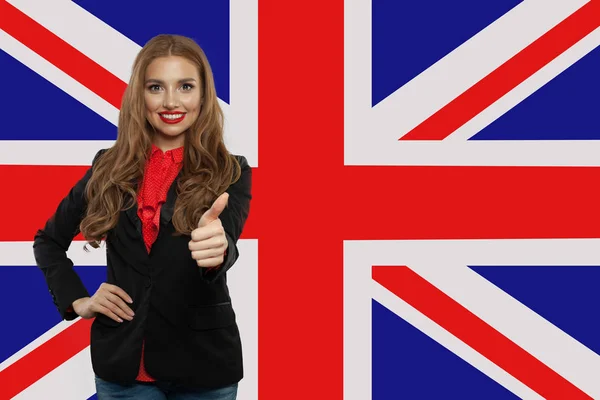 Портрет счастливой красивой девушки с большим пальцем на флаге Великобритании — стоковое фото