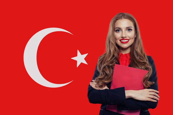 Cute smiling brunette girl student with book against Turkish flag — Stock Photo, Image