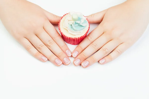 Manos de mujer con uñas manicuradas francesas sosteniendo cupcake en blanco — Foto de Stock