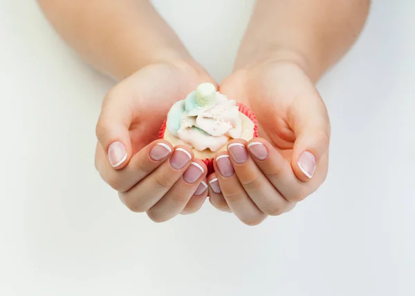 Woman's hands with french manicure nails holding sweet puncake — Stock Photo, Image