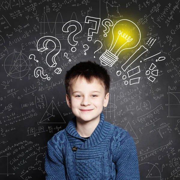 Souriant enfant écolier avec ampoule sur fond avec des formules — Photo