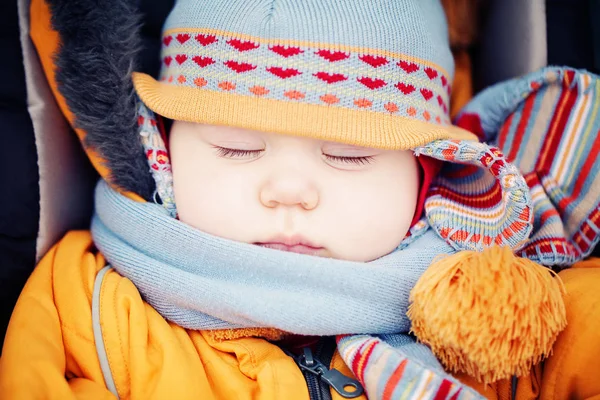 Baby in muts en sjaal slapen buiten. — Stockfoto