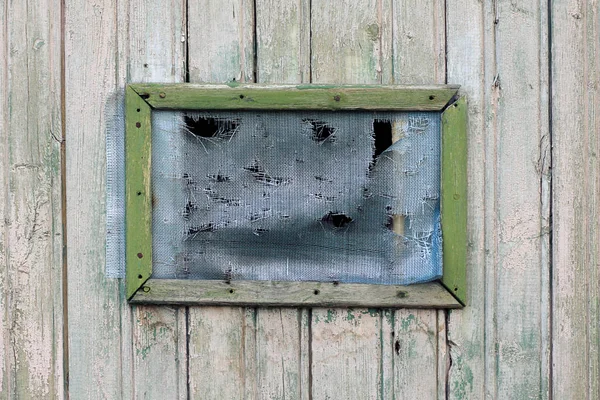 Gammalt hål i rutnät på den äldre gröna träfönster — Stockfoto