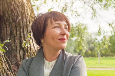 Gülümseyen Olgun kadın açık havada istirahat, yüz kapatmak portre